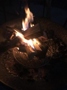 Small fire in a firepit warms the evening with its glowing flames.