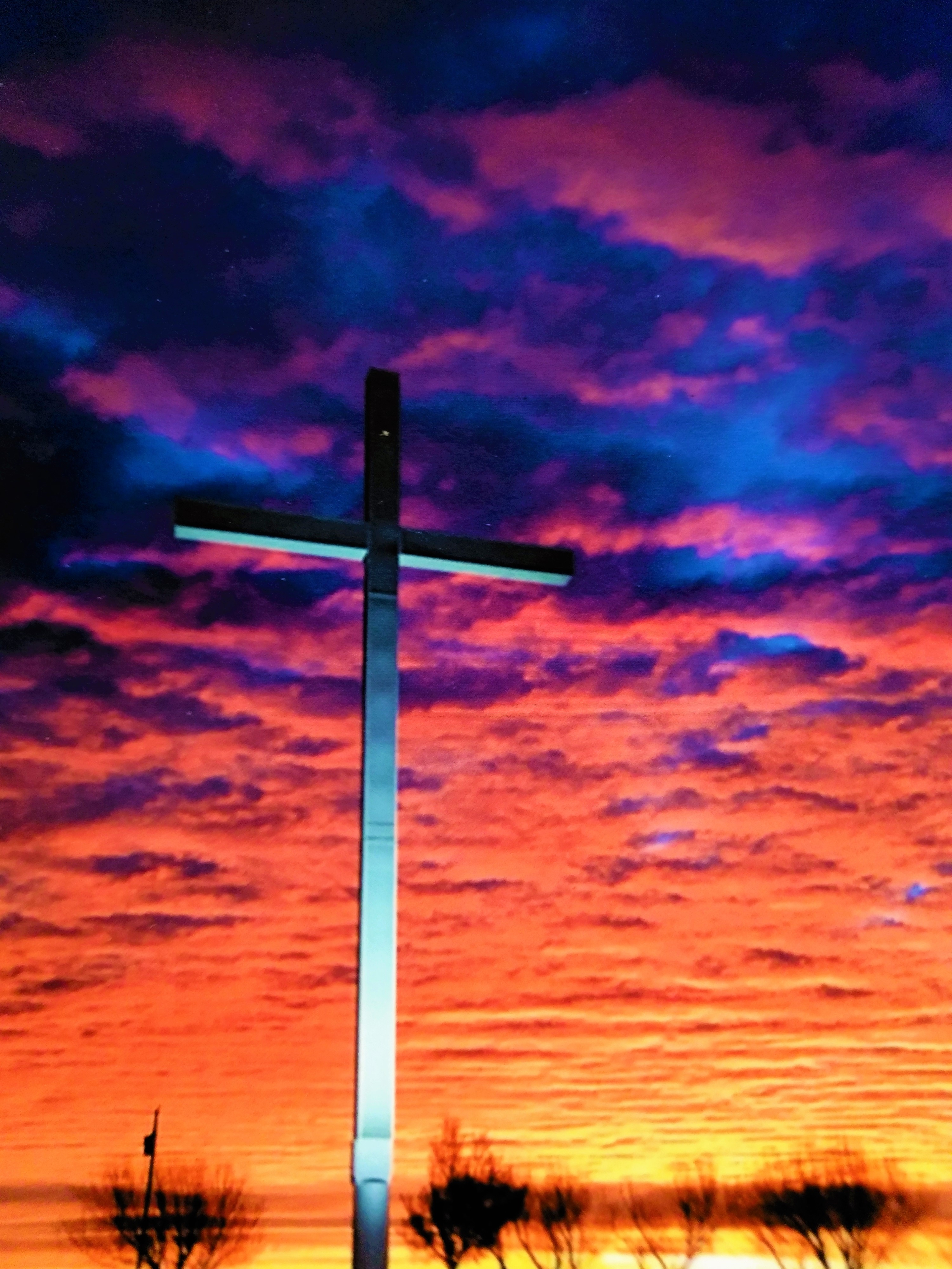 White cross with sunrise in the background. The photo is taken at Restlawn Memorial Gardens at sunrise.