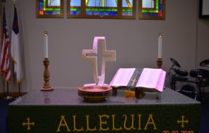 Open Bible and cross on communion table.