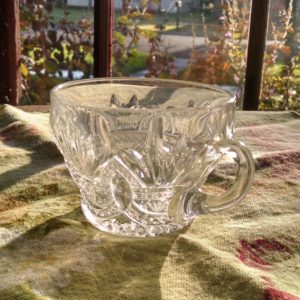 My Momma's clear, crystal punch cup. It sits in front of a window with the sun shining through the glass.