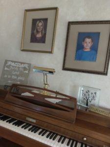 A piano with portraits above it.