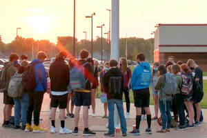 students gathered around a school flagpole praying